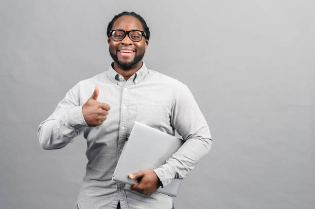 istock Smart African-American man using a laptop, isolated on grey 1370005620