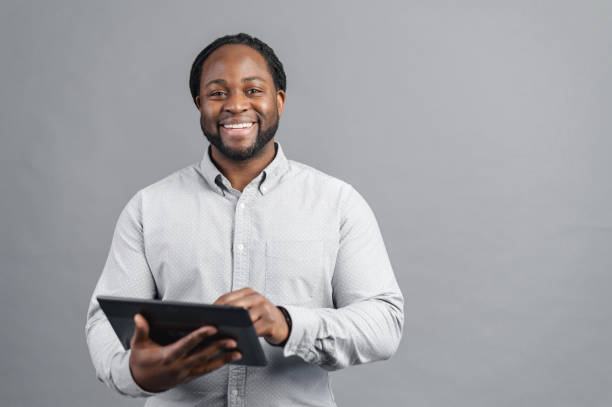 istock Smiling African-American man holding digital tablet isolated on grey 1370005892