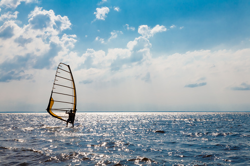 Man using windsurfing wing and a hydrofoil board while while engaging in extreme sports on the sea and ocean water. Kitesurfing.