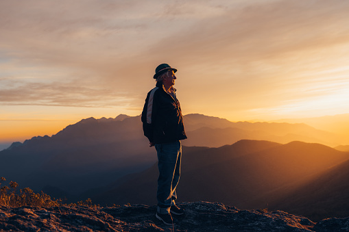 Senior man enjoying sunset at the top of the mountain