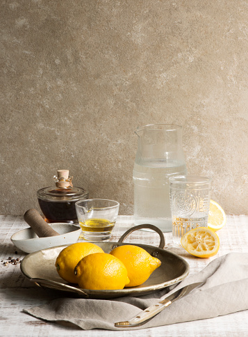 Balsamic vinegar, Olive oil, Lemons, and a water jar on an Italian farm table.