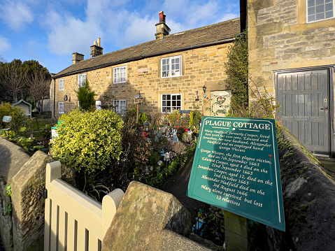 Eyam, United Kingdom - December 31, 2021: In 1665 residents of these cottages succumbed to the Bubonic Plague outbreak in the Peak District village of Eyam in Derbyshire, UK. The Bubonic plague ran its course over 14 months and one account states that it killed at least 260 villagers, with only 83 surviving out of a population of 350.