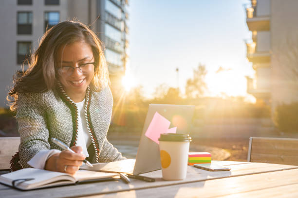 istock Happy woman taking notes while working outdoors 1370013150