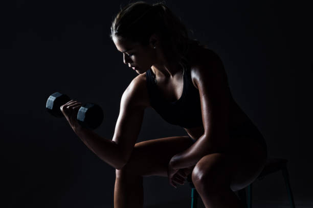 Attractive Young Woman Working Out with Dumbbell Weights stock photo