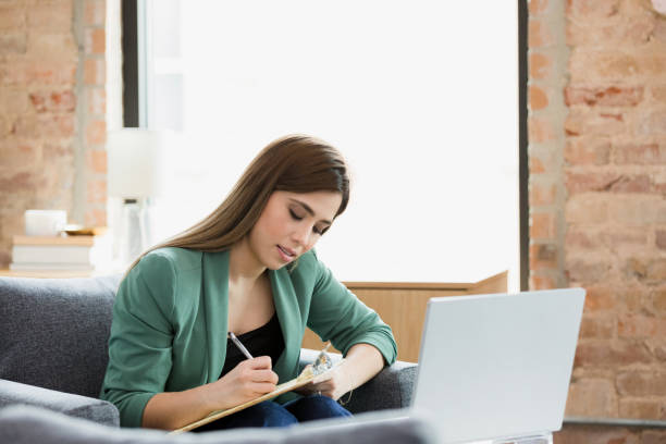 istock Young adult professional takes notes during online class 1370014514