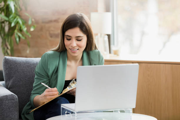 istock Female therapist takes notes during online session with unseen client 1370014534