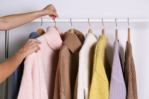 Mujer eligiendo suéter en el estante sobre fondo blanco, primer plano photo