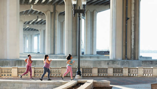Three multiracial women running on city waterfront