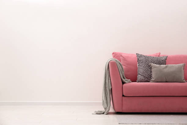 istock Comfortable pink sofa near white wall indoors, space for text. Simple interior 1370015877