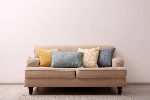 istock Comfortable beige sofa near light wall indoors, space for text. Simple interior 1370015914