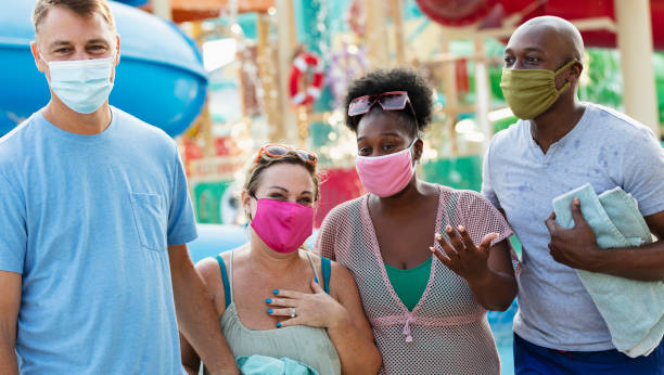 istock Two multiracial couples have fun at water park, in masks 1370016183