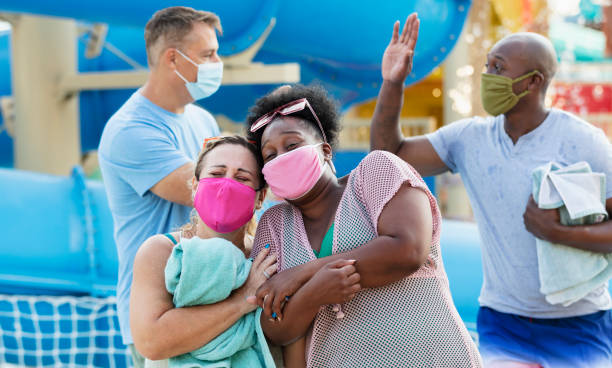 istock Two multiracial couples have fun at water park, in masks 1370016242