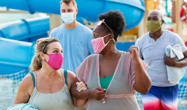 istock Two multiracial couples have fun at water park, in masks 1370016245