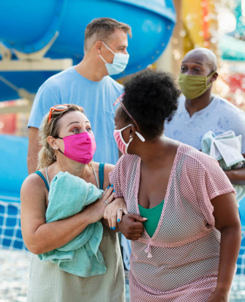 istock Two multiracial couples have fun at water park, in masks 1370016246