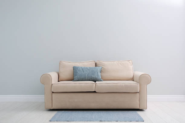 istock Comfortable beige sofa near light wall indoors, space for text. Simple interior 1370016266