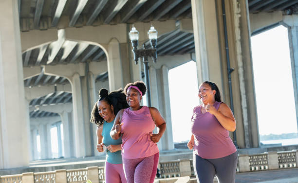 Three multiracial women running on city waterfront