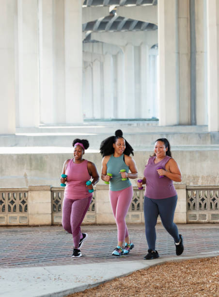 Three multiracial women running on city waterfront