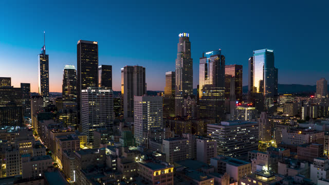 Aerial time lapse of Downtown Los Angeles at sunset, flying backwards over the Historic Core and Looking towards the Financial District skyscrapers.