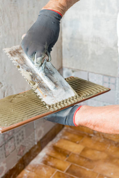 istock Close up Senior Man Hands Applying Adhesive on Tile 1370017531
