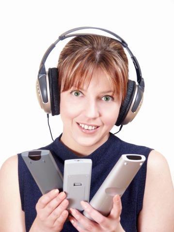 young woman with headphones and 3 remote controles, smiling