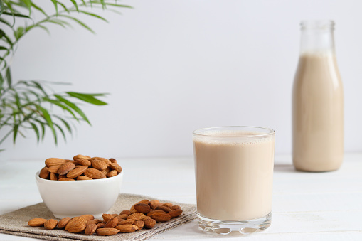 Almond milk in drinking glass on the table. Vegan plant-based product. Healthy food concept, lactose free food, Selective focus.