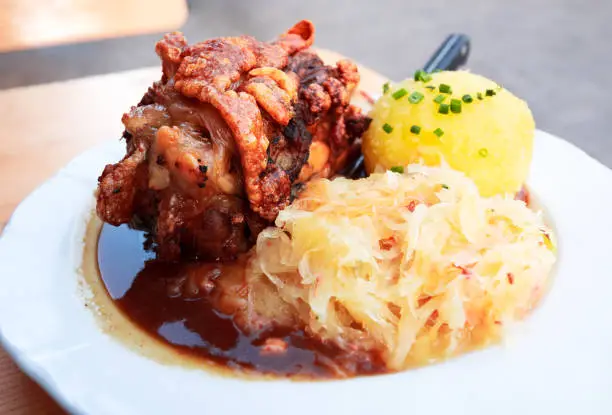 Schweinshaxe, traditional Bavarian cuisine with roasted ham hock (pork knuckle) with cabbage and potato dumpling.
