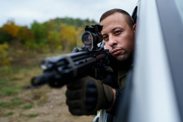istock One man special force police or terrorist holding automatic weapon shooting and aiming from the car anti-terrorist unit on the mission under attack in vehicle copy space side view 1370037127