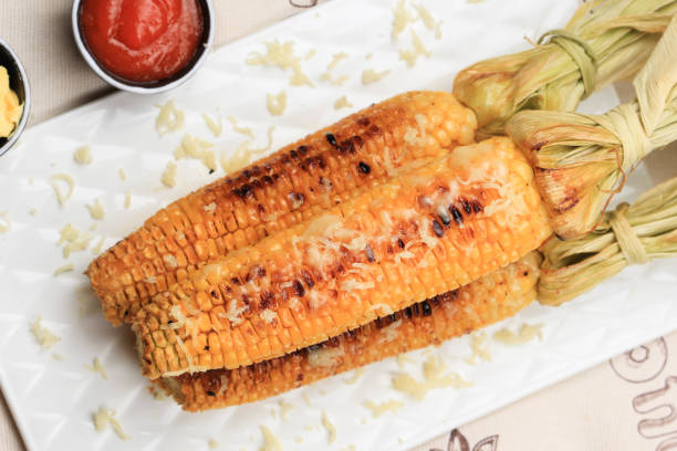 istock Grilled Sweet Corn with Butter and Shredded Mozarella. Served on White Plate 1370038088