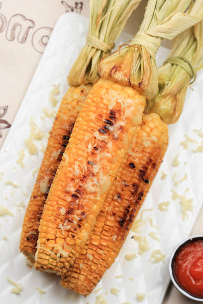 istock Grilled Sweet Corn with Butter and Shredded Mozarella. Served on White Plate 1370038089