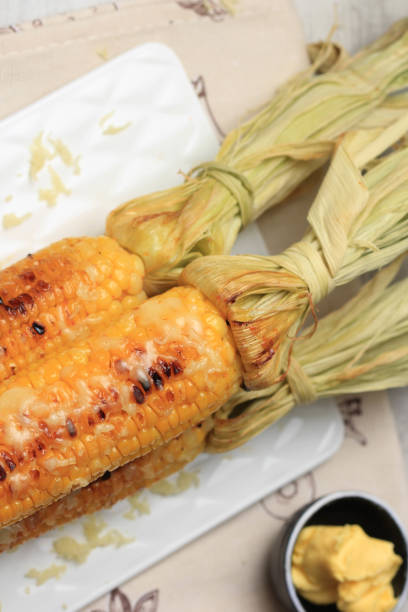 istock Grilled Sweet Corn with Butter and Shredded Mozarella. Served on White Plate 1370038099