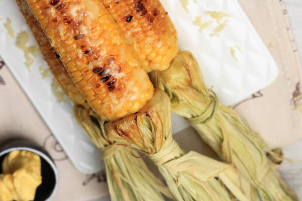 istock Grilled Sweet Corn with Butter and Shredded Mozarella. Served on White Plate 1370038103