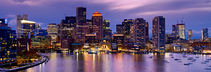 Panoramic drone shot of Downtown Boston, Massachusetts at sunset, taken from over the harbor and looking past Fan Pier and the mouth of Fort Point Channel towards office towers, Rowe's Wharf ferry terminal and other buildings on the waterfront. 

Authorization was obtained from the FAA for this operation in restricted airspace.