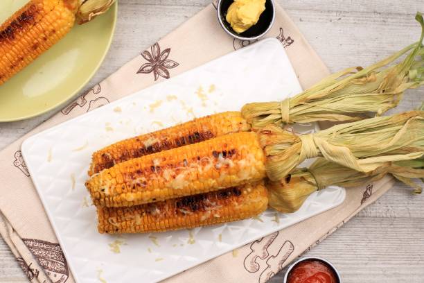 istock Grilled Sweet Corn with Butter and Shredded Mozarella. Served on White Plate 1370038283