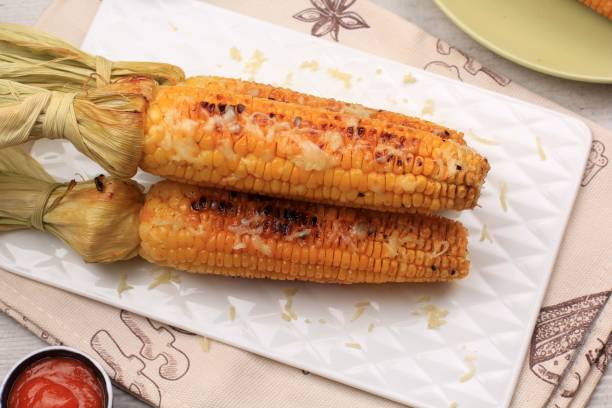 istock Grilled Sweet Corn with Butter and Shredded Mozarella. Served on White Plate 1370038284