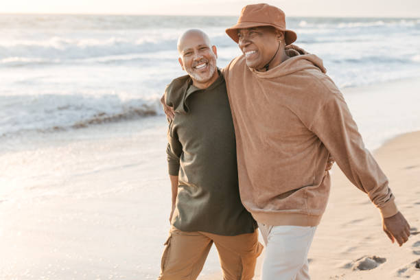 istock Senior couple walking on a beach together 1370046389