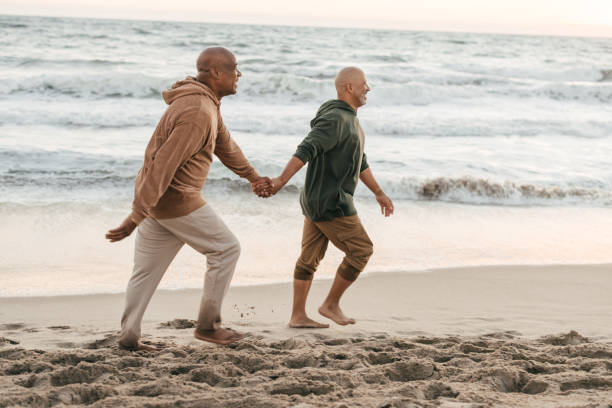 istock Gay couple walking on the beach 1370046412