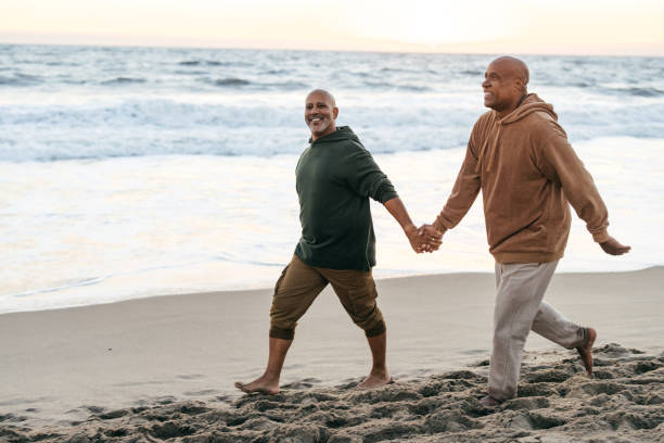 istock Gay couple walking on the beach 1370046418