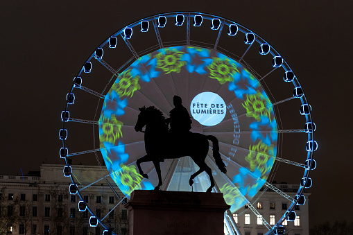 Festival of Lights - fête des lumières - in Lyon. On December 8, the monuments are illuminated, here, the wheel, behind Louis XIV statue, on Place Bellecour. The origins of this festival date to 1643, in honor of the Virgin Mary who protected the city from the plague,in 1643. Since then, the city has been illuminated every year, around December 8th. Lyon, in France. December 8th, 2010