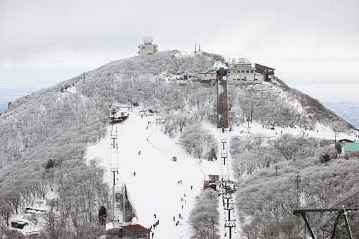 High up on a winter mountain skiers are having fun on the slopes.