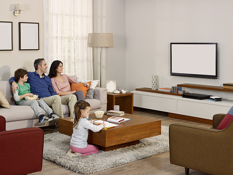 Family with 2 kids watching tv in a modern house