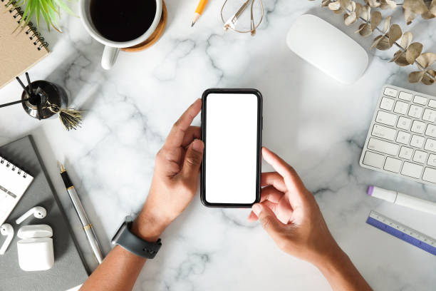 istock Above view young man holding smart phone with white screen on marble table. 1370061266