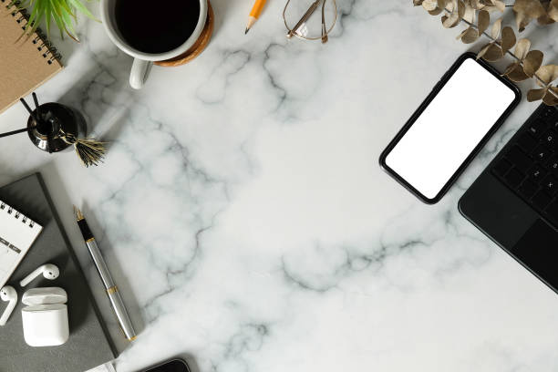 istock Top view smart phone, wireless earphone, coffee cup and notebook on marble table. 1370061270