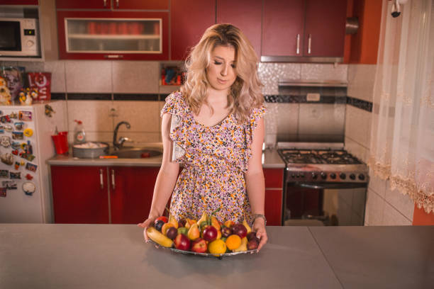 istock Lovely woman eating fruit in the kitchen 1370065980