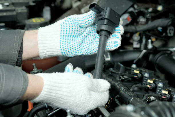 An auto mechanic holds a new ignition coil in his hands. Close-up. Installing a new ignition coil.