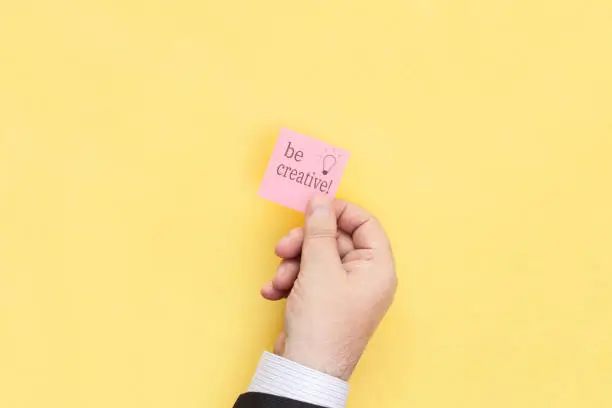 Sticky note with inscription Be creative.  Motivational statement.