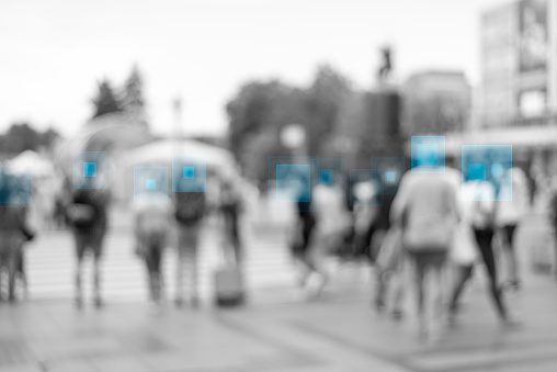 Face detection and recognition of citizens, face recognition and personal identification technologies in street surveillance cameras, crowd of passers-by with graphic elements. Privacy and personal data protection.