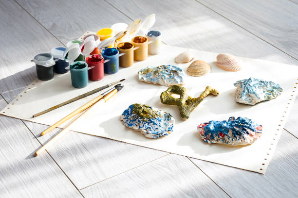 istock Child's craft place with shells have been painted different colors, paintbrushes and gouache paints. Child painting seashells for DIY project. 1370081063
