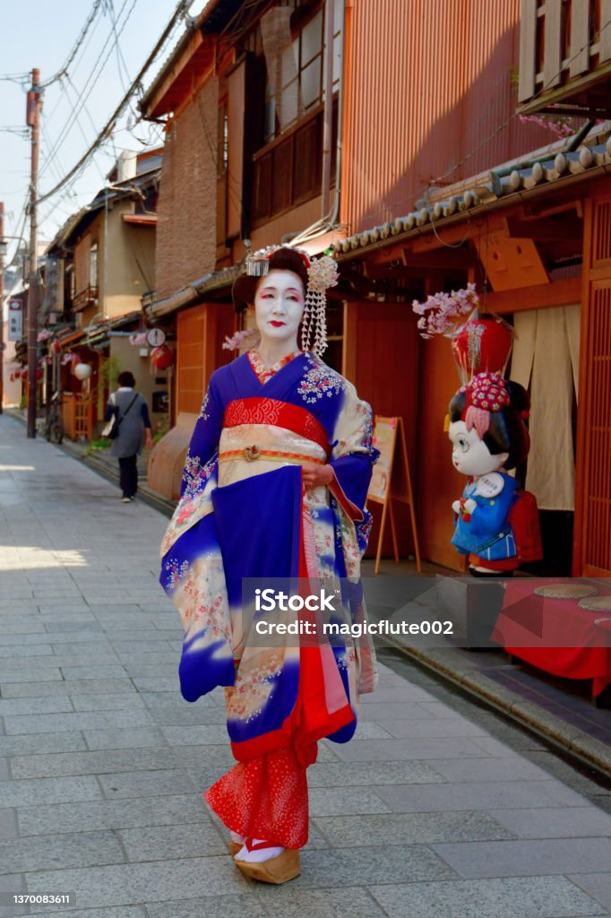 Japanese Woman in Maiko's Costume Walking on Gion's Street, Kyoto A Japanese woman in Maiko’s costume and hairstyle is walking on the street of Miyakawa-cho, Gion, Kyoto. She wears traditional long-sleeved kimono with long dangling sash and her hair is elaborately decorated with seasonal flower-featured hairpins. 50-59 Years Stock Photo