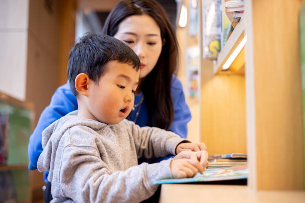 istock Mother with boy reading a book in library 1370088581