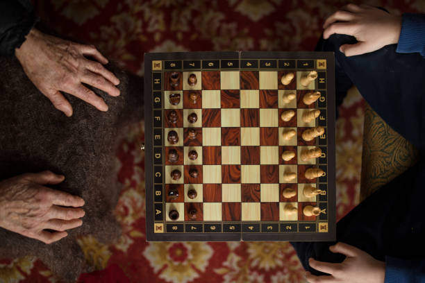 古い世代と若い世代の間のチェスの戦い。トップビューチェスボード手で。 - board game playing child family ストックフォトと画像